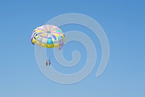 Colorful parasailing parachute against a clear blue sky.