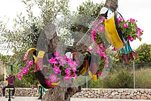 Colorful parrot decorations, hanging on the tree, made with car tires and pink petunias
