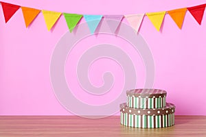 Colorful party flags hanging on pink background and gift box on