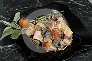 Colorful Pasta with Sauce, olivevs, Tomatoes in Black Plate. top view. food. Heart-Shaped Macarons on Black Table. Italian food.