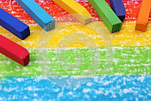 Colorful pastel chalks on drawing of rainbow, closeup. Space for text
