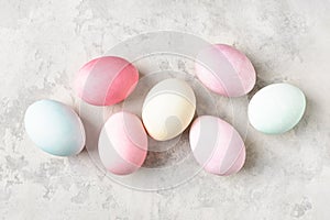 Colorful pastel dyed Easter eggs on light grey background, flat lay.