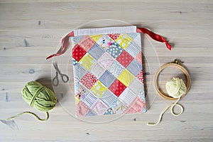 Colorful patchwork drawstring bag, green and yellow yarn, scissors, embroidery hoop