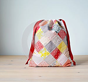 Colorful patchwork drawstring bag on wooden table