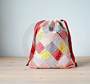 Colorful patchwork drawstring bag on wooden table photo