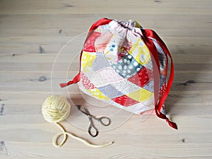 Colorful patchwork drawstring bag, yellow yarn and scissors