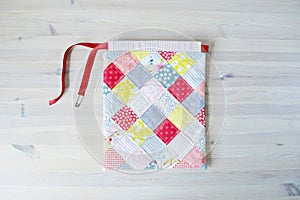 Colorful patchwork drawstring bag, yellow yarn and scissorsColorful patchwork drawstring bag and safety pin