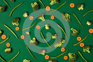 Colorful pattern of Broccoli, carrots and green beans on a green background