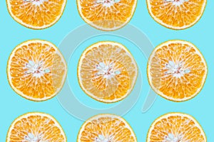 Colorful pattern of cutted orange fruits, isolated on background of cyan or aqua menthe color.