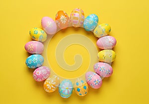 Colorful patterned easter eggs arranged in a circle on yellow background