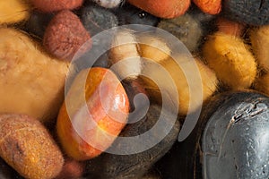 Colorful pebbles partly covered by shallow water and ice crystals