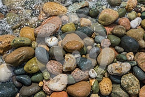 Colorful pebbles in sea at Mediterranean beach. Texture, background concept.