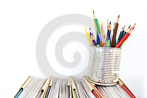 Colorful pencil in old zine tin on the book isolated white background.