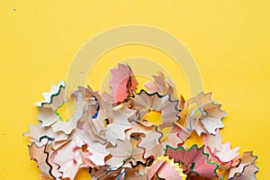 Colorful pencil shavings on yellow background. Back to school concept. Copyspace