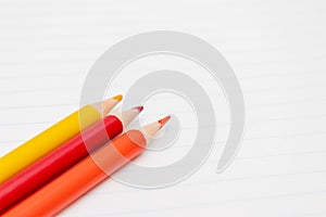 Colorful pencils on the background of a white lined sheet of notebook close-up with copy space