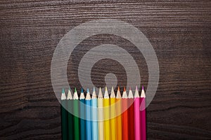 Colorful pencils over brown table background