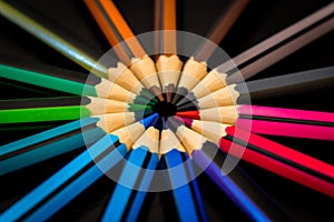 Colorful pencils circle on dark background