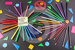 Colorful pencils in circles and title Back to school written on the piece of paper on the chalkboard