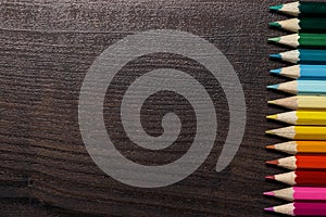 Colorful pencils on dark brown table background