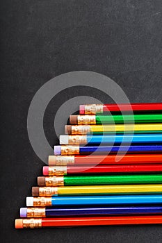 Colorful pencils with erasers in a row on a black background