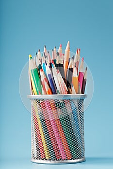 Colorful pencils in a metal jar on a blue background