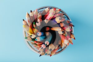 Colorful pencils in a metal jar on a blue background