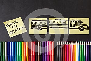 Colorful pencils, titles Back to school and school bus drawn on the pieces of paper on the chalkboard