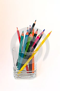 Colorful pencils in a transparent glass