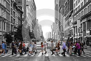 Colorful people walking across a busy intersection in a black and white Manhattan cityscape in New York City