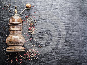 Colorful peppercorns and old pepper mill on the black