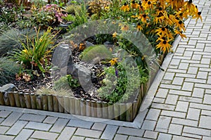 A colorful perennial flowerbed at the entrance to the garden bordered by a decorative wooden palisade. from the back it is connect