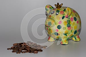 A colorful piggy bank with a steepled cent coins isolated on a white underground and background