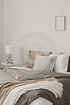 Colorful pillows in king size bed with duvet and blankets in hygge inspired bedroom