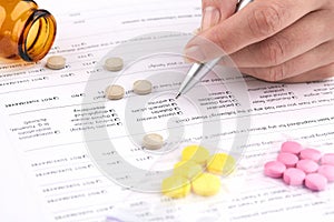 Colorful pills, brown vial and hand writing on medical questionnaire form