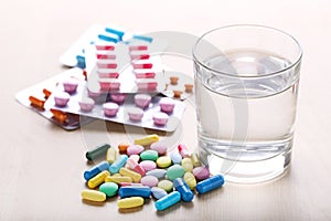 Colorful pills with glass of water