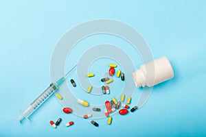 Colorful Pills, Medicine bottle and disposable syringe closeup on blue background. Health pharmacy pharmacology concept with Copy