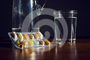 Colorful pills medicine capsule with glass of water on table