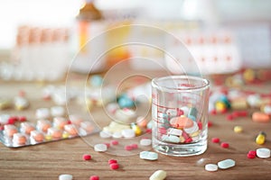 Colorful pills and medicines in glass cup on table