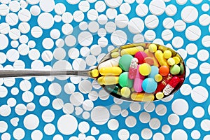 Colorful pills in spoon on a blue background