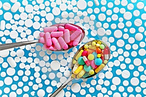 Colorful pills in spoons on a blue background