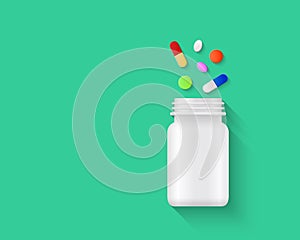 Colorful pills, tablets and capsules spilling out of blank white pill bottle on green background