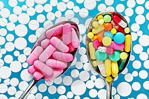 Colorful pills in two spoons on a blue background