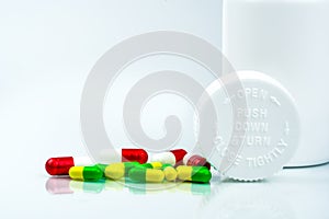 Colorful pills on white background and plastic bottle with blank label and copy space. Childproof packaging. Child resistant pill