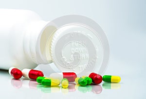 Colorful pills on white background and plastic bottle with blank label and copy space. Childproof packaging. Child resistant pill