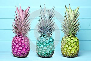 Colorful pineapples on a pastel blue wood background