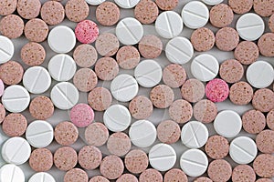 Colorful pink, brown, and white medical pills, tablets and capsules from above color photo.