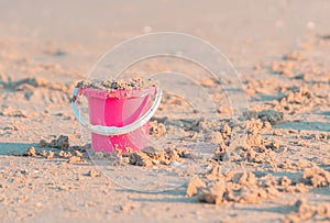 Pink plastic bucket full of sand for kid summer vacation toy concept