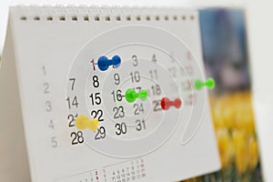 Colorful pins push marking on a calendar. Busy schedule