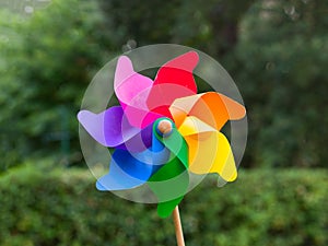 Colorful pinwheel in a garden trees blurred in background