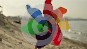 Colorful pinwheel spins joyfully on a sandy beach. Nostalgia of childhood summers, beach tourism, and the pursuit of happiness.